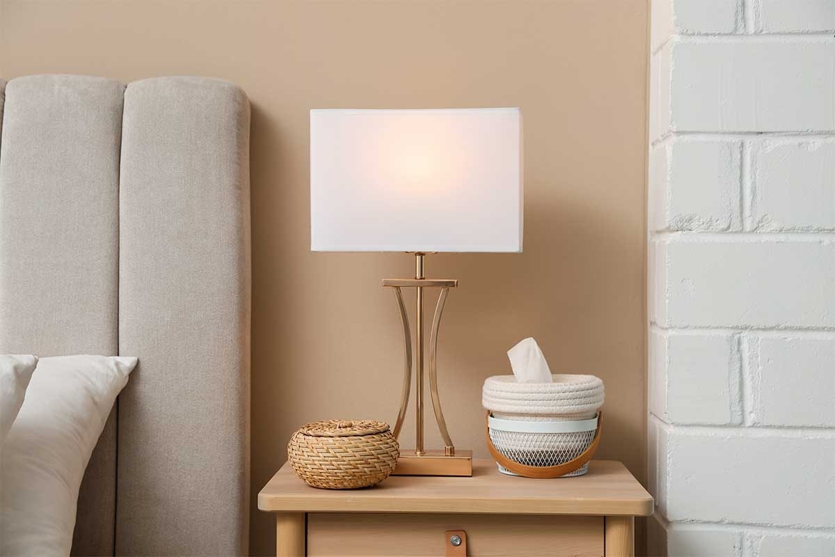 A bedside table with a lamp and baskets