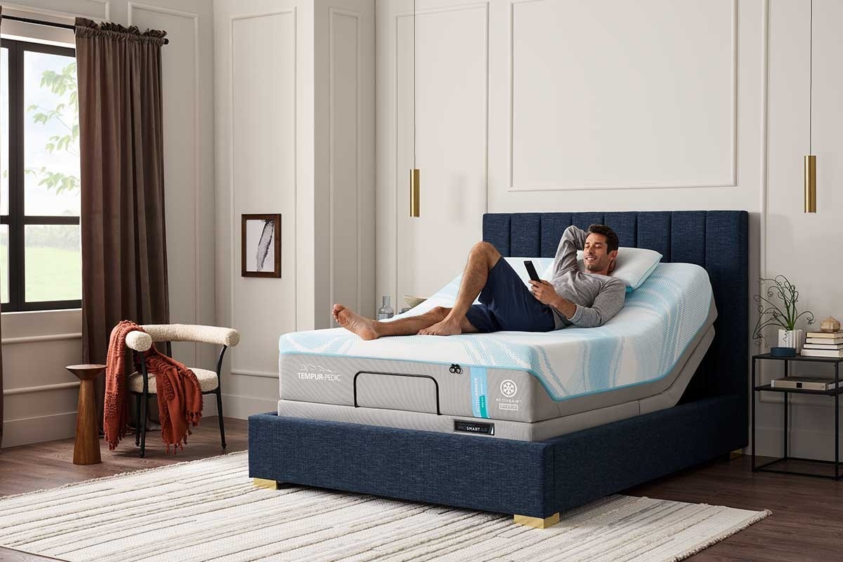 A man with a remote in hand lounging on an TEMPUR-ActiveBreeze in a styled room