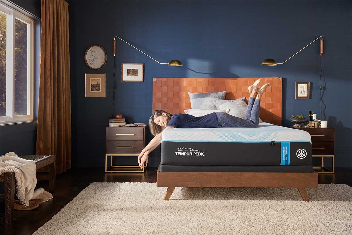 A woman lying on a TEMPUR-LuxeBreeze soft mattress in a styled room