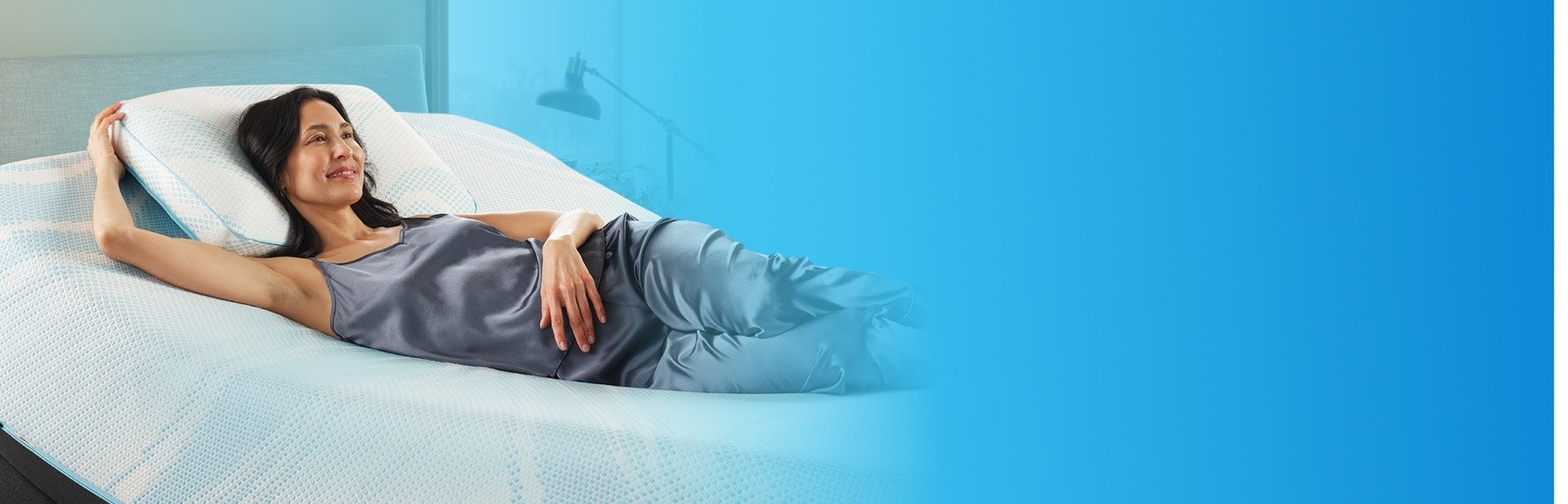 woman on a naked adjustable mattress set with one arm tucked behind a pillow
