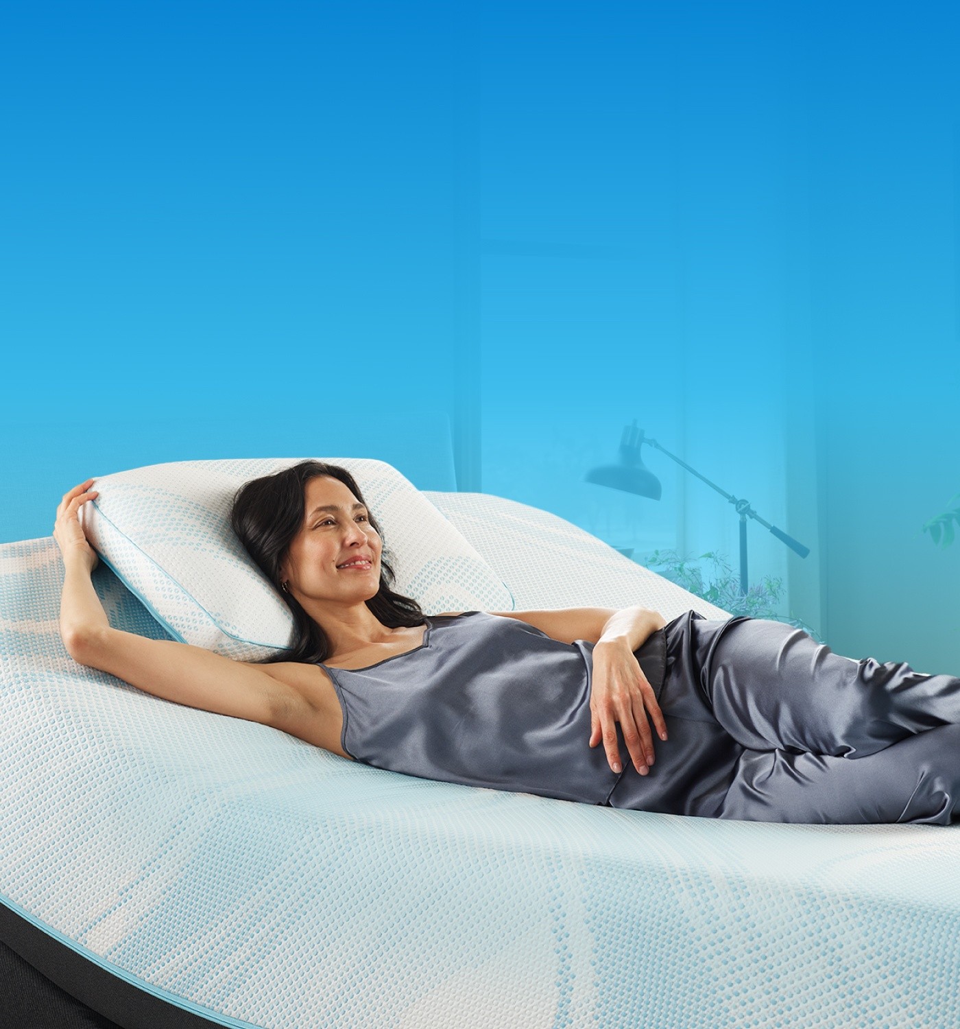 woman on a naked adjustable mattress set with one arm tucked behind a pillow